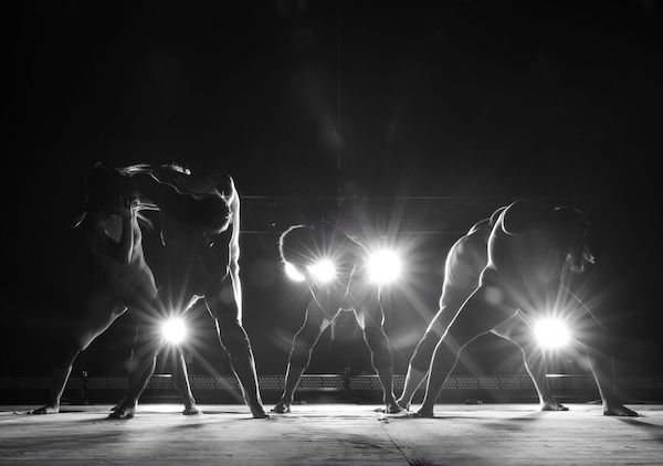 Backlit dancers spread their legs