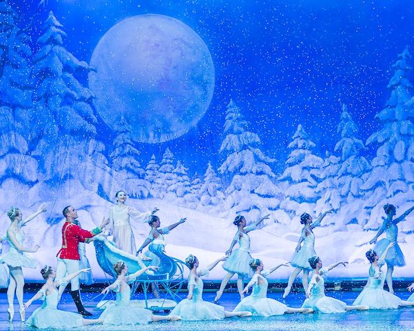 A sled with ballet dancers against a snowy backdrop