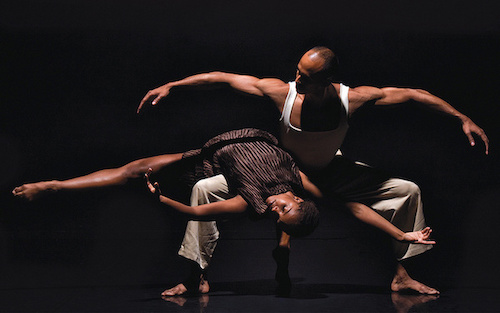 A male dancer holds a female dancer stretched across his knee