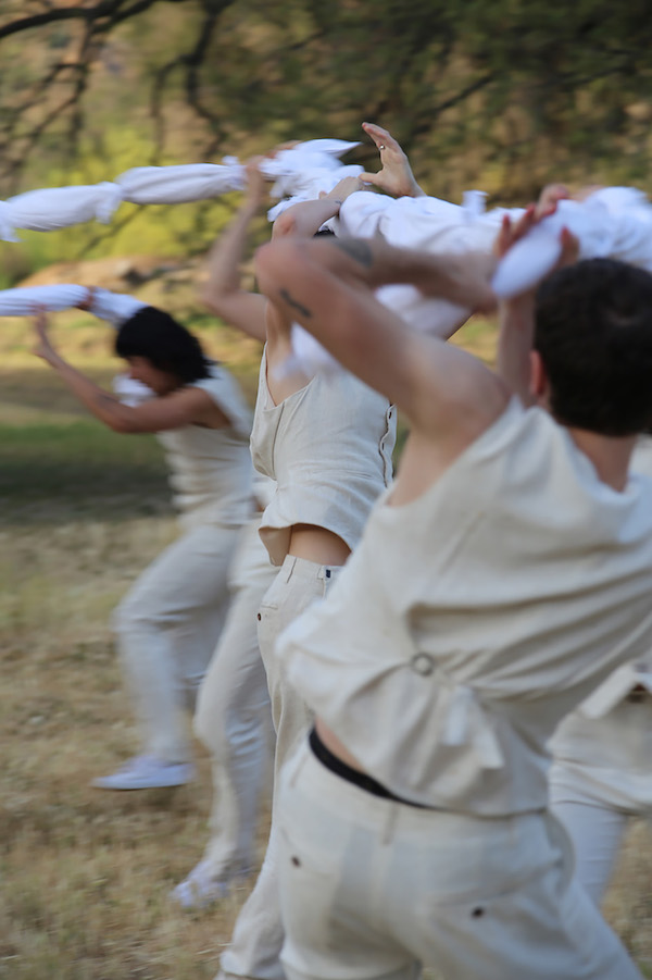 A group wrestles a white fabric