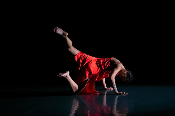 A dancer in red extends her leg behind her