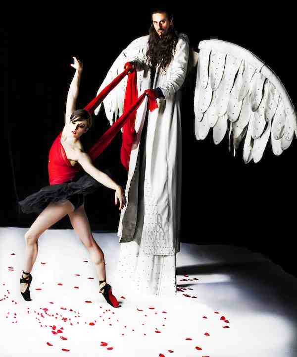 A ballet dancer in front of a angel on stilts