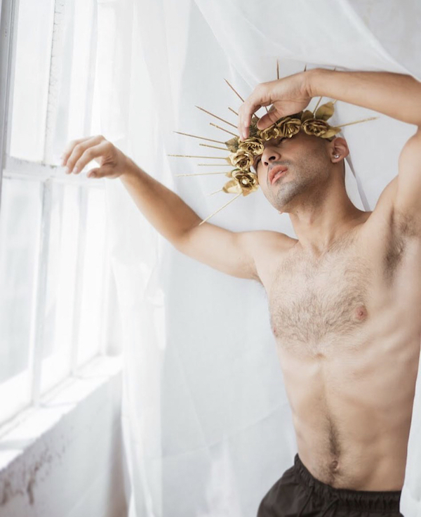 A shirtless man with a crown of gold flowers