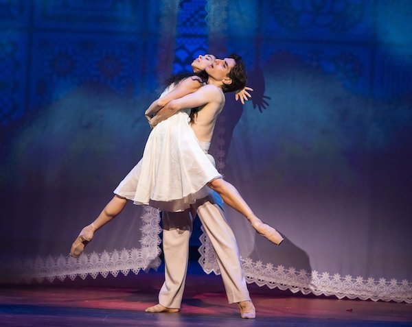 A male dancers lifts a female dancer in a white dress