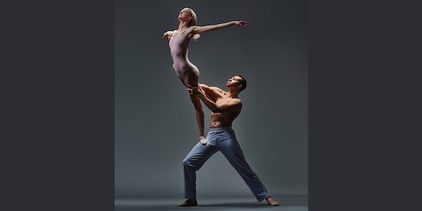 A male dancer holds a female dancer on his thigh