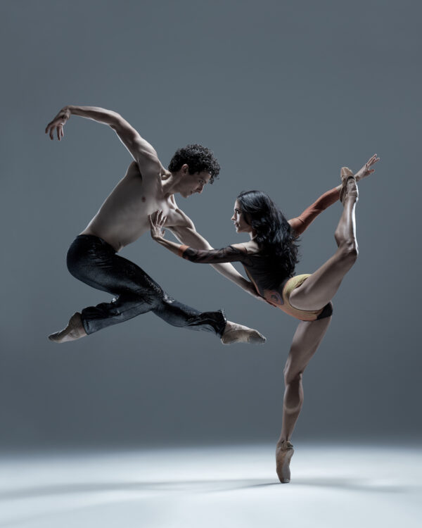 A male dancer jumps above a female dancer