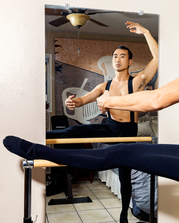 A dancer with leg on bar faces a mirror